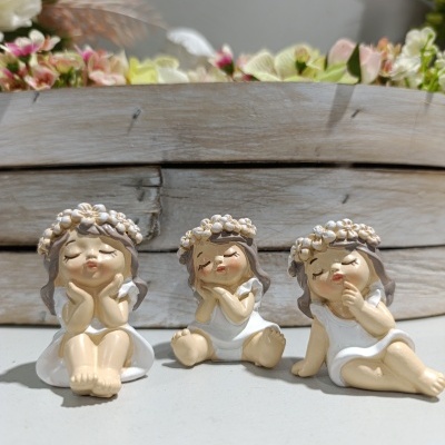 Três estatuetas decorativas de raparigas com coroas de flores e vestidos brancos