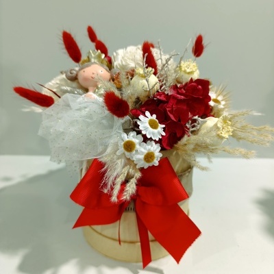 Arranjo floral em vaso decorado com flores coloridas, laço vermelho e figura de fada