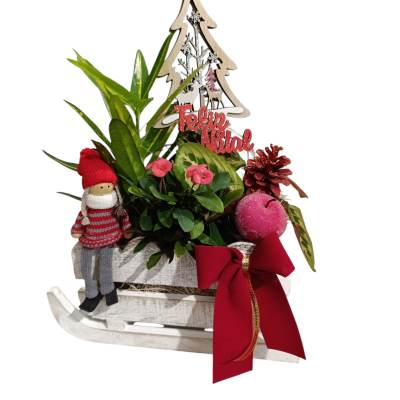 Arranjo decorativo de Natal com trenó, plantas, flores, enfeites vermelhos e boneco em malha.