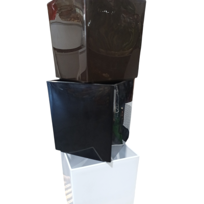 Três vasos quadrados empilhados nas cores castanho escuro, preto e branco.