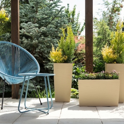 Cadeira azul moderna e vasos bege com plantas em terraço ao ar livre