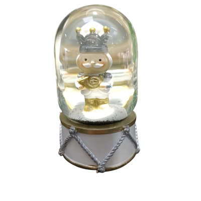 Globo de neve com personagem de rei dentro de cúpula de vidro sobre base em forma de tambor