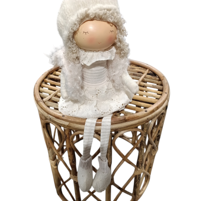 Boneca decorativa branca sentada em banco de madeira trançada