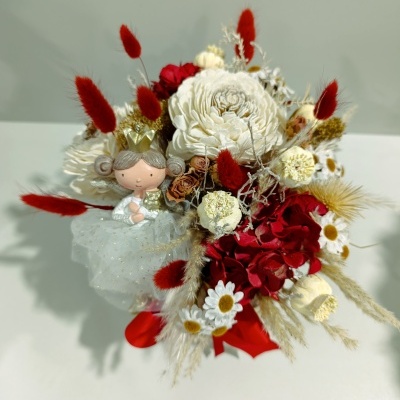 Arranjo floral com boneca de princesa e flores vermelhas, brancas e bege