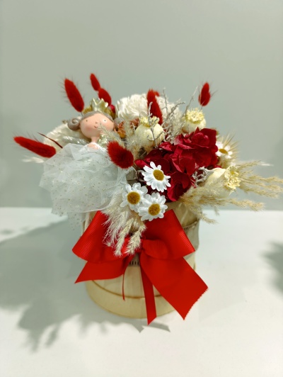 Arranjo floral em vaso decorado com flores coloridas, laço vermelho e figura de fada