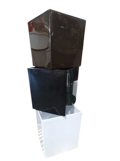 Três vasos quadrados empilhados nas cores castanho escuro, preto e branco.