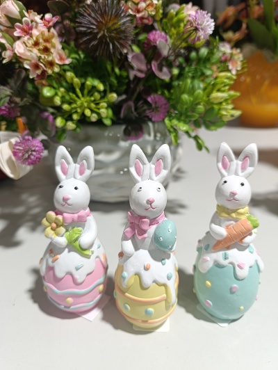Três coelhos decorativos de cerâmica com cores pastel e padrões de ovos de Páscoa