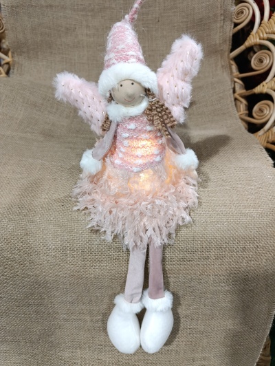 Anjo decorativo cor-de-rosa com plumas e asas peludas sentado sobre tecido bege