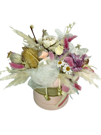 Arranjo floral decorativo com flores secas e figura de fada numa caixa rosa redonda