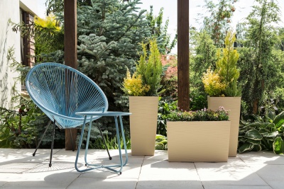 Cadeira azul moderna e vasos bege com plantas em terraço ao ar livre