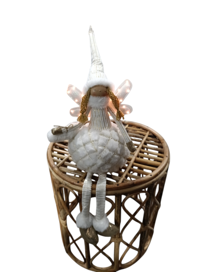 Boneca decorativa branca sentada numa mesinha de madeira redonda