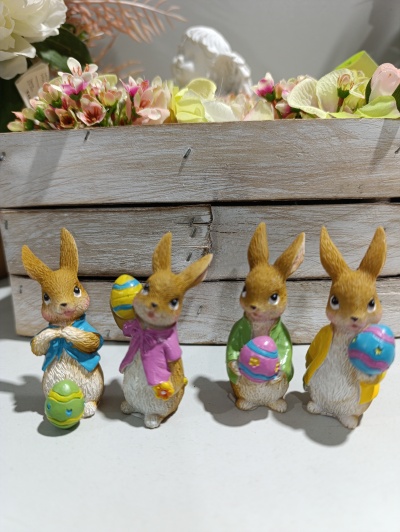 Figuras decorativas de coelhos com ovos de Páscoa coloridos e caixa de madeira com flores