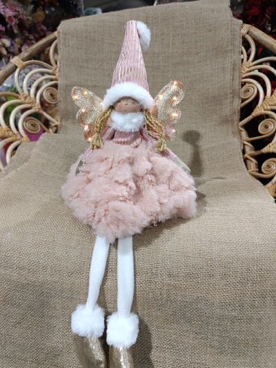 Boneca decorativa rosa com asas douradas sentada sobre cadeira de palha