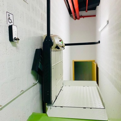 Elevador de plataforma para cadeiras de rodas instalado numa parede branca com texto LIFTECH Move up