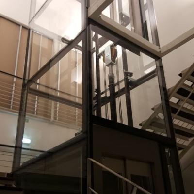 Elevador de passageiros em vidro e metal entre escadas interiores