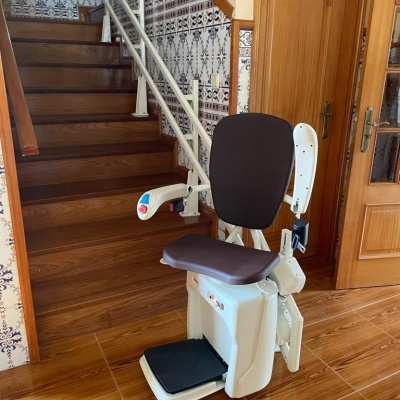 Cadeira elevatória para escadas com assento castanho em escadaria interior
