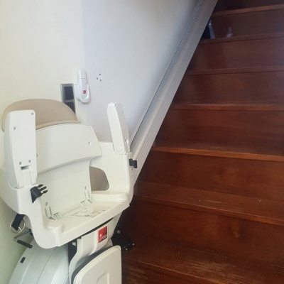 cadeira para escadas branca com assento bege junto a escada de madeira escura