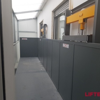 Elevador de carga metálico cinza e amarelo em corredor interno