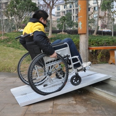 Pessoa em cadeira de rodas a utilizar rampa portátil de acessibilidade exterior