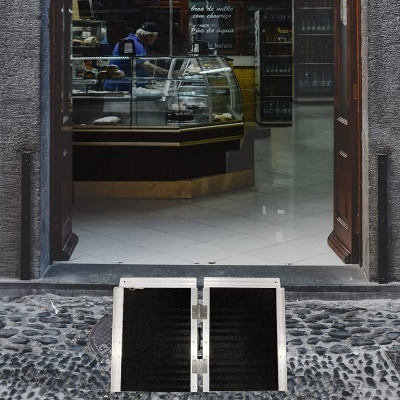 Entrada de loja com balcão de vidro e texto de produtos no interior.