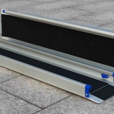 Rampa portátil de alumínio com superfícies antiderrapantes pretas e detalhes azuis sobre chão de ladrilhos