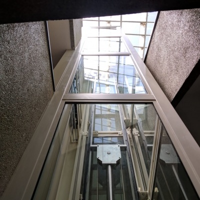 Elevador de vidro com estrutura branca dentro de edifício