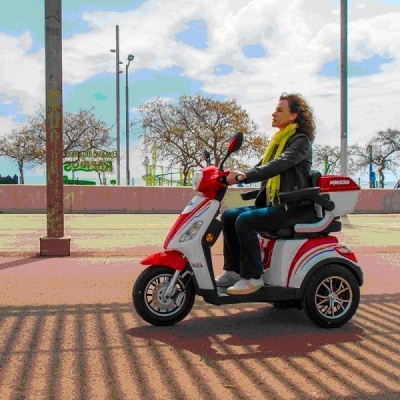 Motociclo elétrico vermelho e branco de três rodas com mulher a conduzir