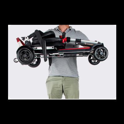 Carrinho de bebé dobrado com estrutura preta e vermelha segurado por pessoa