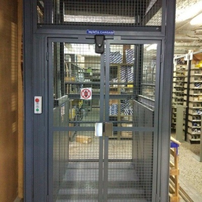 Elevador de cargas metálico cinzento em ambiente industrial