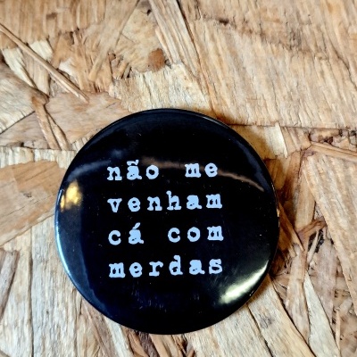 Botton preto com texto em branco sobre superfície de madeira