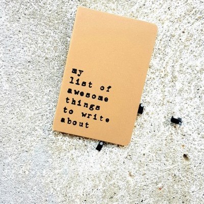 Caderno castanho claro com texto preto sobre parede cinzenta