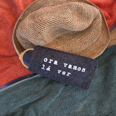 Chapéu de palha sobre toalhas vermelha e verde com óculos e placa preta com texto