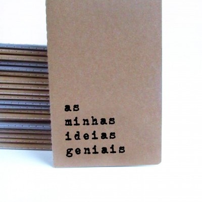 Caderno castanho claro com texto 'as minhas ideias geniais'