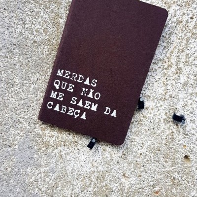 Caderno castanho com frase branca sobre superfície rugosa cinzenta