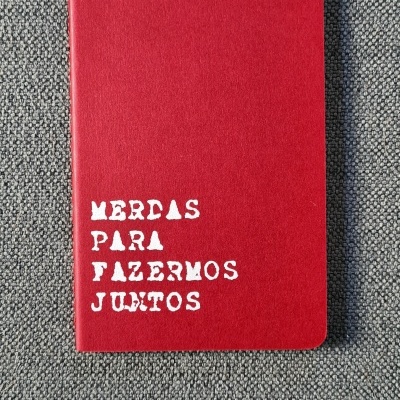 Caderno vermelho com texto branco em superfície cinza