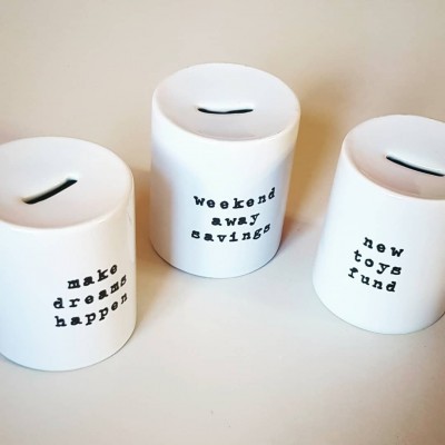 Três mealheiros brancos com texto em preto sobre fundo branco