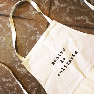 Avental de cozinha branco com texto em preto 'mostre de culinária'