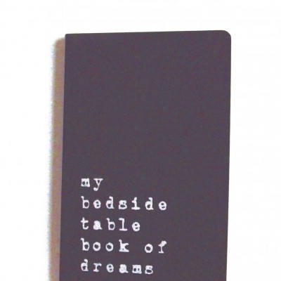 Caderno preto com texto branco 'my bedside table book of dreams'.