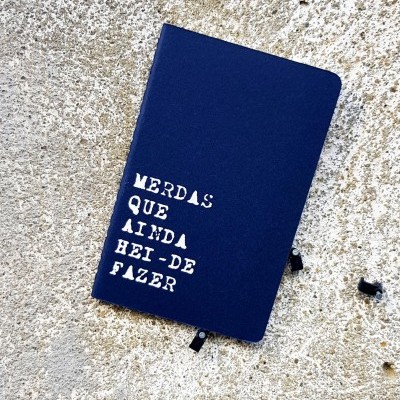 Caderno azul com capa dura e texto branco sobre superfície de pedra clara
