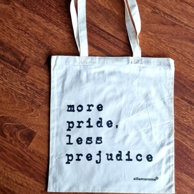 Saco de tecido branco com texto preto 'more pride, less prejudice'