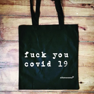 Saco de tecido preto com texto branco sobre piso de madeira