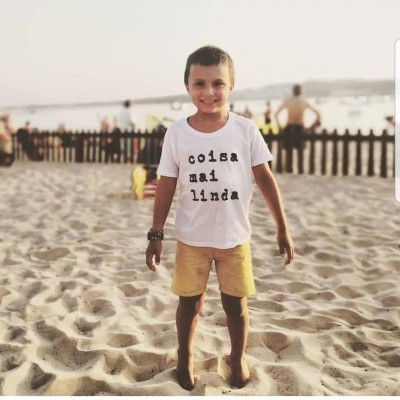 Criança na praia com t-shirt branca e calções amarelos