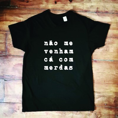 T-shirt preta com texto em branco na frente sobre fundo de madeira