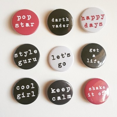 Nove bottons redondos com frases em inglês em fundo preto, branco e vermelho