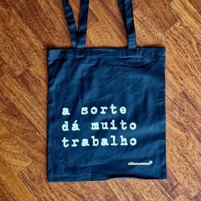 Mala azul de tecido com texto branco sobre chão de madeira