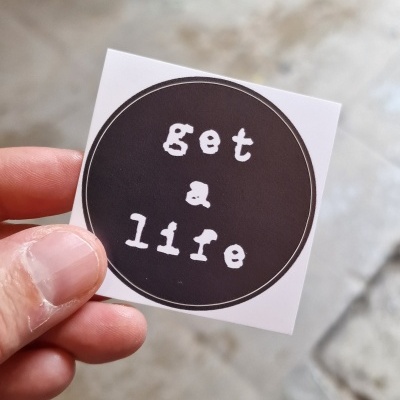 Etiqueta quadrada com texto 'get a life' em fundo preto