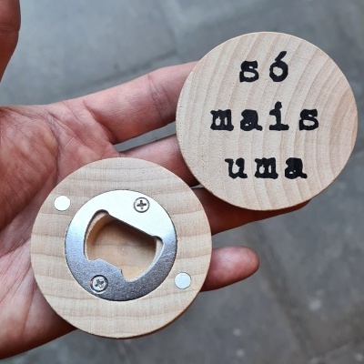 Abridores de garrafa redondos em madeira clara, com texto 'só mais uma' e parte metálica para abrir garrafas