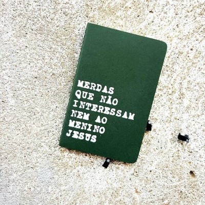 Caderno verde com texto branco sobre parede rugosa creme