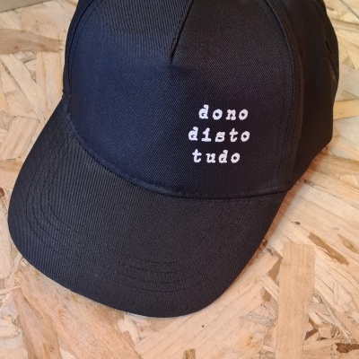 Boné preto com frase 'dono disto tudo' bordada em branco