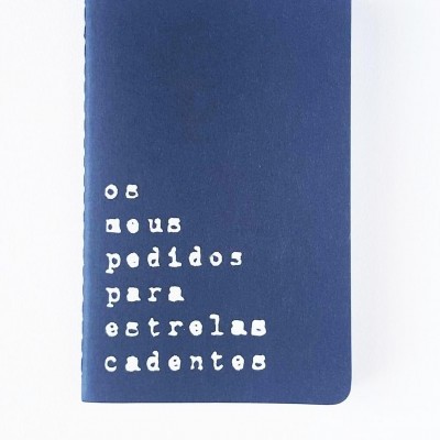 Caderno azul com texto branco 'os meus pedidos para estrelas cadentes' destacado